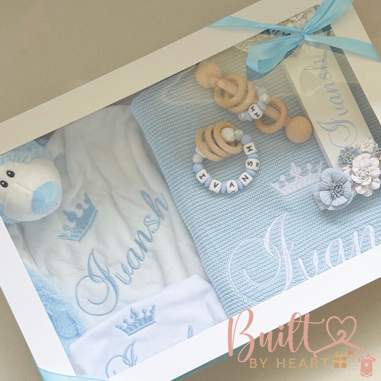 Personalised blue newborn gift hamper with embroidered blanket, clothing, plush toy and wooden baby accessories