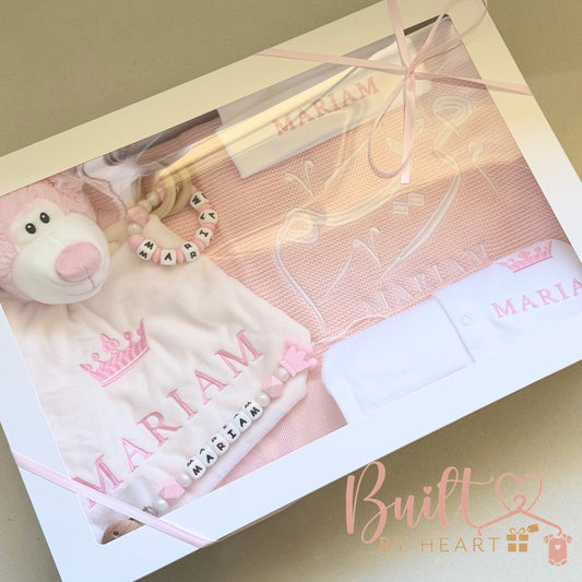 Personalised pink newborn gift hamper with embroidered blanket, baby outfit, plush toy and matching name accessories